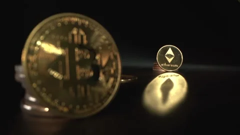 Bitcoin BTC and Etherium ETH reflect on the table with black background. Focus Stock Footage 129803225