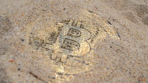 Bitcoin BTC coin close up. Bitcoin coin covered sand lying in the sand close-up Stock Footage 294213158
