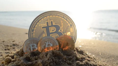 Bitcoin BTC coin in sand on sandy beach of sea coast on a sunny morning close-up 動画素材 246502300