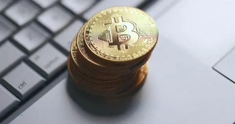 Bitcoin BTC cryptocurrency. Stack of golden coins on laptop keyboard. Hand takes Stock Footage 149359129