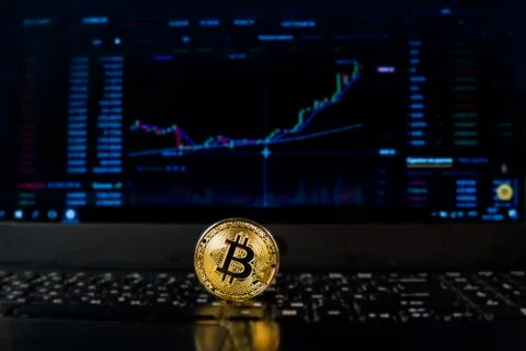 A bitcoin coin on the background of a chart displaying the price on a currenc Stock Photos
