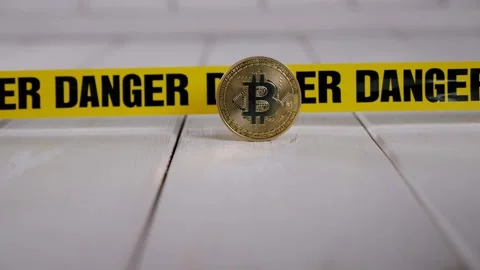 A bitcoin coin, in the background a yellow tape with the inscription DANGER. Stock Footage 329913613