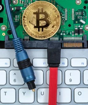 Bitcoin coin on circuit board of computer with fiber optic cables and keyboar Stock Photos