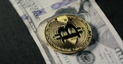 Bitcoin coin on the dollar banknotes spinning on a black background Stock Footage 79039778