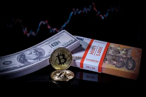 A bitcoin coin lies next to a stack of dollar notes and a stack of euro notes Stock Photos
