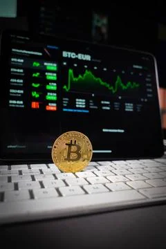 A bitcoin coin is standing on a computer keyboard and in the background is... 写真素材