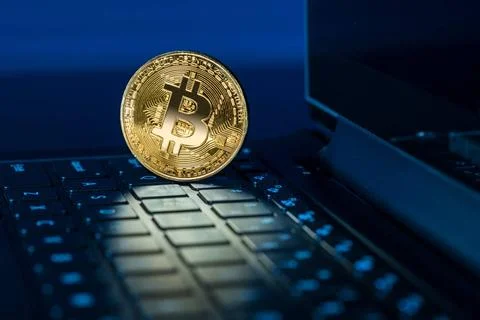 Bitcoin coin standing on keyboard of computer Single bitcoin coin standing... Stock Photos