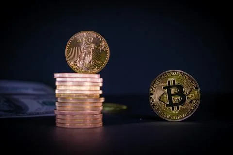 Bitcoin coin stands next to a stack of other gold coins Stock Photos