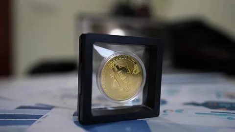 Bitcoin Coin in Transparent Frame with Financial Charts, A gold Bitcoin coi.. Stock Footage 304876996