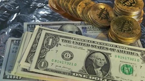 Bitcoin coins and stack of dollars on silver table, slowly rotating background Stock Footage 266991311