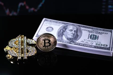 Bitcoin coins lie next to a stack of $100 bills and a diamond-studded dollar Stock Photos