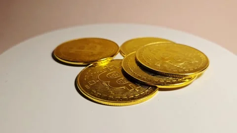Bitcoin Coins Resting on a White Rotating Platform, Symbolizing Digital Wealth Stock Footage 303494191