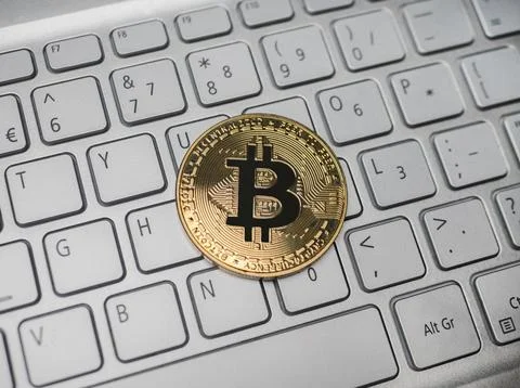 Bitcoin cryptocurrency coin lying on white laptop keyboard Фото