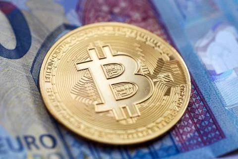 Bitcoin cryptocurrency, a gold coin, lies on a twenty-euro bill Stock Photos