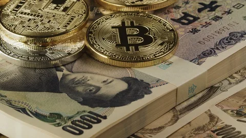 Bitcoin cryptocurrency on top of a bundle of japanese yen banknotes. Fintech As Stock Footage 122351727