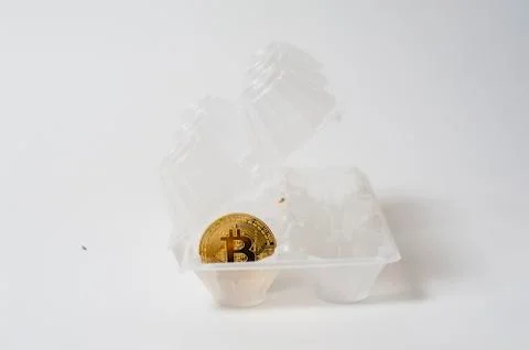 Bitcoin electronic coin inside an egg holder, white background Stock Photos