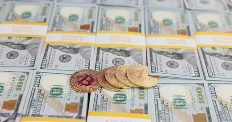 Bitcoin gold coins on a stack of hundred dollar bills Stock Footage 287552755