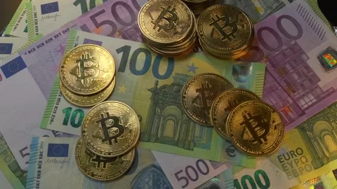 Bitcoin gold coins on top of stack of euro bills different value, top view. Stock Footage 266985948
