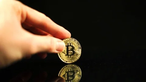 Bitcoin in hand on a black background. Mirror reflection of a coin Stock Footage 92760845