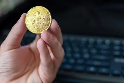 Bitcoin in hand on keyboard background Stock Photos