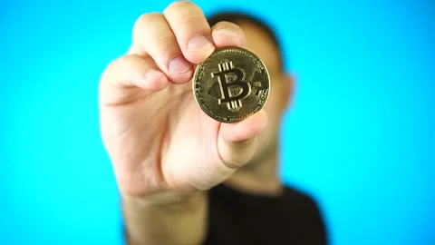 Bitcoin holder man on blue background. Man showing gold Bitcoin cryptocurrency Stock Footage 160920453