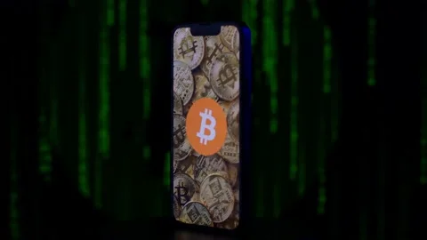 Bitcoin on an iPhone with green code in the background Stock Footage 231748313
