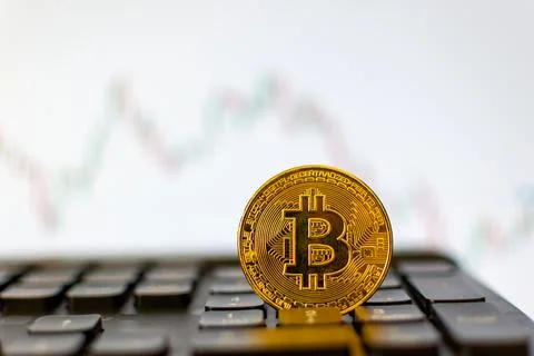 Bitcoin on the keyboard and a graph in the background Stock Photos