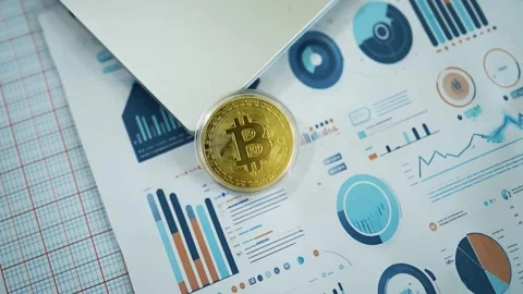 Bitcoin on Laptop with Financial Charts, A Bitcoin coin placed on a laptop .. Видео 304881053