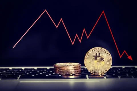 Bitcoin on laptop keyboard with decrease price graphic. Red arrow go down Stock Photos