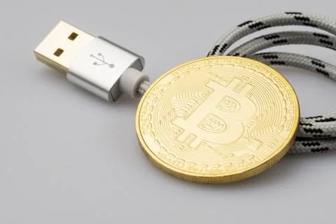 Bitcoin leaning on USB cable isolated on white background Stock Photos