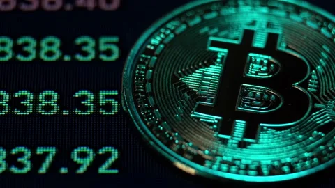 Bitcoin lies against the background of the screen on which its price is rapidly  Stock Footage 152649904