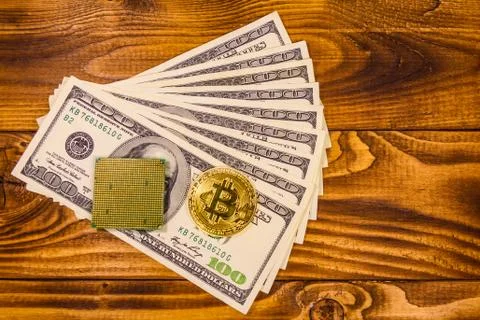 Bitcoin, microprocessor and one hundred dollar bills on wooden table. Top vie Foto stock