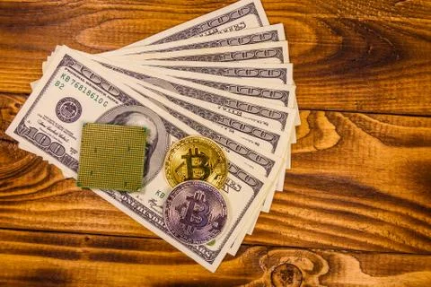 Bitcoin, microprocessor and one hundred dollar bills on wooden table Foto stock