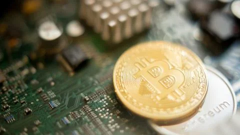 Bitcoin mining process - gold coin on computer circuit board Stock Photos
