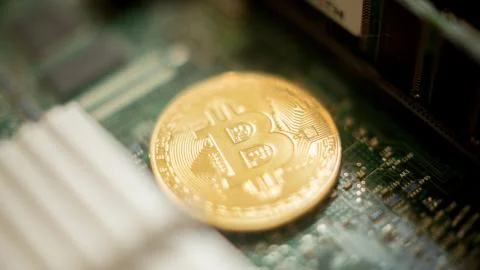 Bitcoin mining process - gold coin on computer circuit board Fotos de archivo