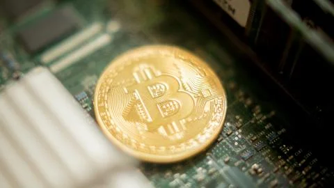 Bitcoin mining process - gold coin on computer circuit board Stock Photos