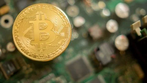 Bitcoin mining process - gold coin on computer circuit board Stock Photos