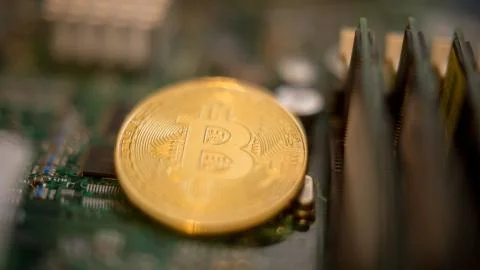 Bitcoin mining process - gold coin on computer circuit board Stock Photos
