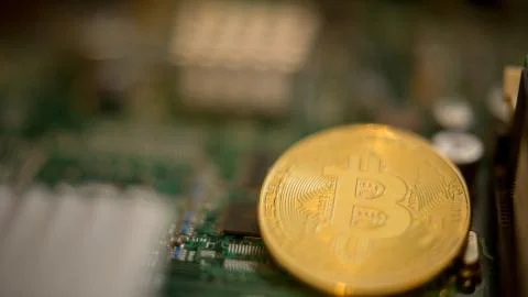 Bitcoin mining process - gold coin on computer circuit board Stock Photos