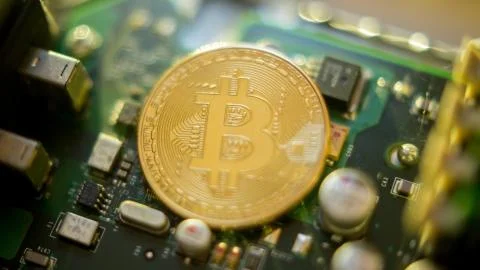 Bitcoin mining process - gold coin on computer circuit board Stock Photos
