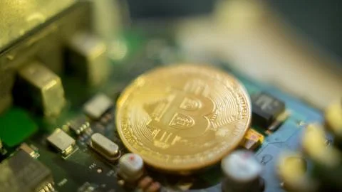 Bitcoin mining process - gold coin on computer circuit board Stock Photos