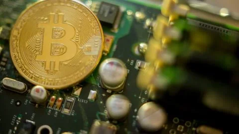 Bitcoin mining process - gold coin on computer circuit board Stock Photos