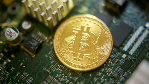 Bitcoin mining process - gold coin on computer circuit board Stock Photos