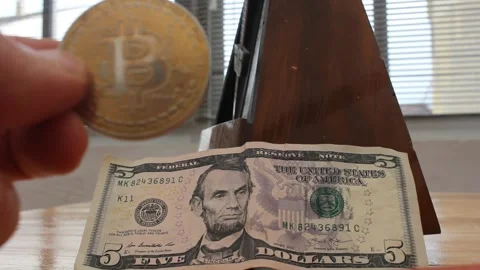 Bitcoin replacing US dollar concept. Metronome ticking with 5 dollar bill a.. Stockbeeldmateriaal 332179159