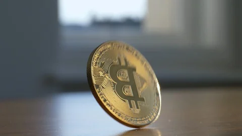 Bitcoin rolls in frame and falls on wooden desk 스톡 동영상 87355676