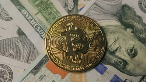 Bitcoin rotating against the background of 100 US dollar bills Stock Footage 234986960
