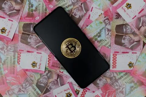 Bitcoin on Smartphon screen and rupiah money Stock Photos