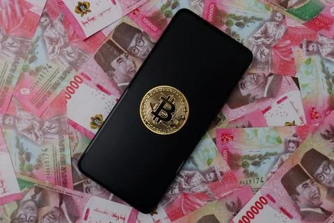 Bitcoin on Smartphon screen and rupiah money Stock Photos