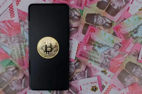 Bitcoin on Smartphon screen and rupiah money Stock Photos