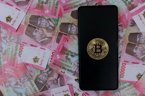 Bitcoin on Smartphon screen and rupiah money Stock Photos